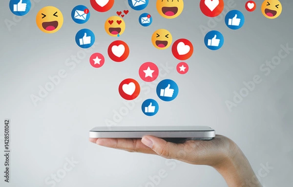 Obraz Smartphone on hand flipping with Floating Social Media Reactions Icons on Light Background idea for social media,online engagement,digital communication,online feedback.