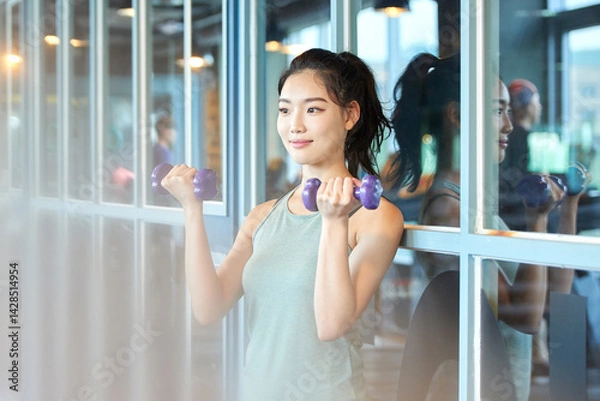 Fototapeta Young Woman Exercising with Dumbbells in Gym
