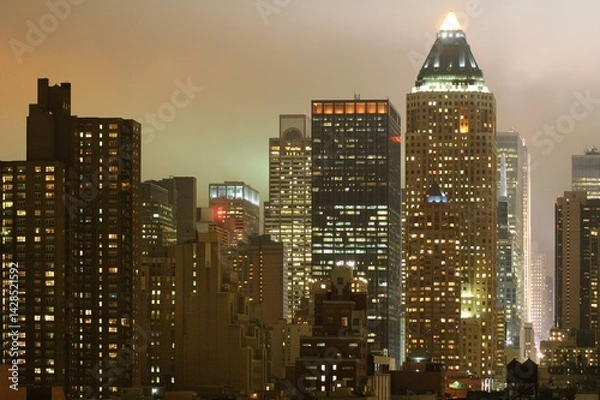 Fototapeta Nighttime New York Skyline With Tall Buildings and Lit Windows