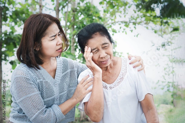 Obraz elderly asian woman feel dizzy and almost faints while walking outside caused by weakness or hot weather , her daughter quickly holds and hugs to help her safe, showing care and support