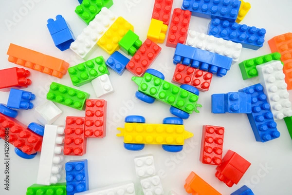 Fototapeta A playful arrangement of colorful plastic building blocks scattered on a white surface, sparking creativity and imagination in design