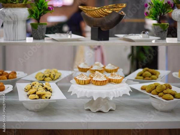Fototapeta Buffet in Hotel. Dessert and Fruits section including lemon meringue tart, cookies and biscuits and fresh bananas. Selective focus on the meringue tart.