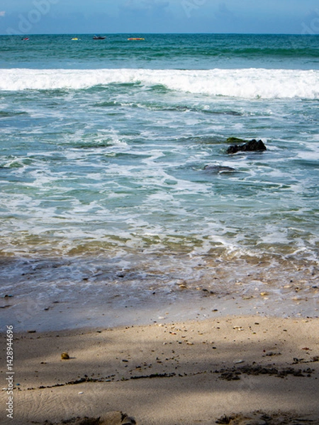 Fototapeta a beach with lots of rocks and calm waves