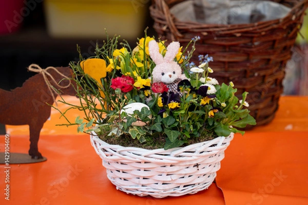 Obraz A basket of flowers with a rabbit in it sits on a table