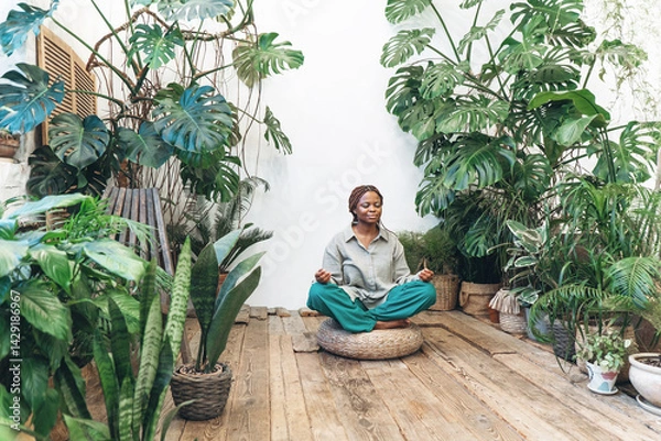 Fototapeta A woman meditates in a calm and serene environment of a green garden
