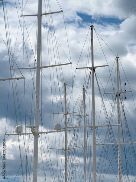 Fototapeta White masts of ships against a cloudy sky