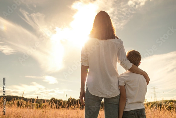 Obraz Mother and son spending time together in nature relaxing in a field looking at the sunset, Motherhood, and family parenting concept.	
