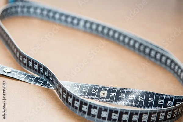 Fototapeta Accessories for sewing lie on background. Measuring tape, thread, fabric and needles for sewing.