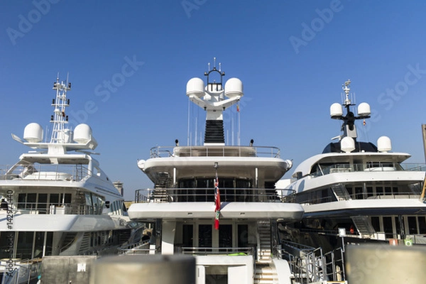 Obraz Modern yachts with massiv radar navigation systems at the stern at a jetty against blue skies