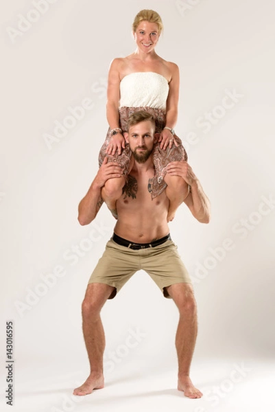Obraz Giant man doing squats with his wife sitting on his shoulders