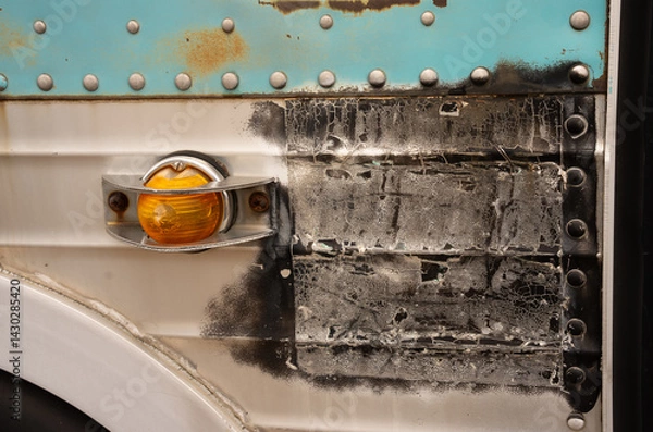 Fototapeta close up of rusty old transportation bus black marks on metal cage covered orange light turquoise rusted metal and bolts close cropped side of the bus just above wheel well horizontal grunge backdrop 