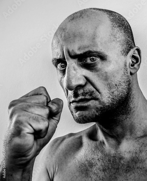 Fototapeta Strong, ugly and angry man shaking fist, bad guy with big nose, black eye, stony unshaven face, old boxer dark portrait