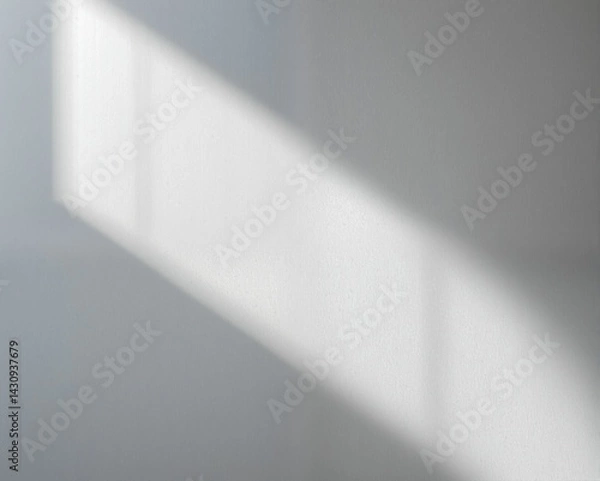 Obraz A soft beam of light casts a gentle shadow on a textured wall, creating a minimalist and serene atmosphere.