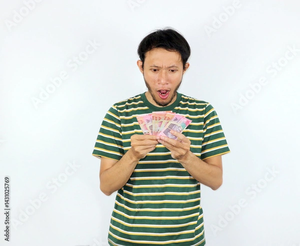 Fototapeta Man Holding Money with Surprised Expression on White Background