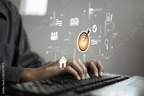 Obraz A person types on a keyboard while various digital business icons such as a target, documents, and users float in mid-air, representing goals and data management.