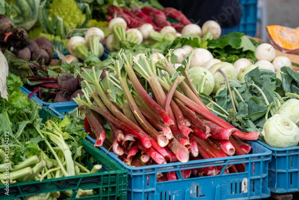 Obraz A blue crate of red radishes sits on a table next to a crate of green vegetables