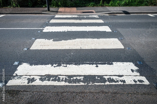 Obraz Road markings of a zebra crossing, some edges nibbled by time, bear witness to endless crossings