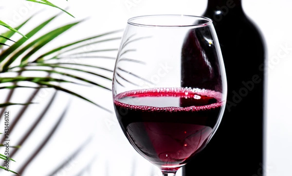 Fototapeta Non-alcoholic, alcohol free, red wine tempranillo in glass with bottle. White background, palm leaves shadows, hard light