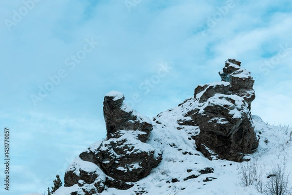 Fototapeta A rocky mountain covered in snow with a blue sky in the background