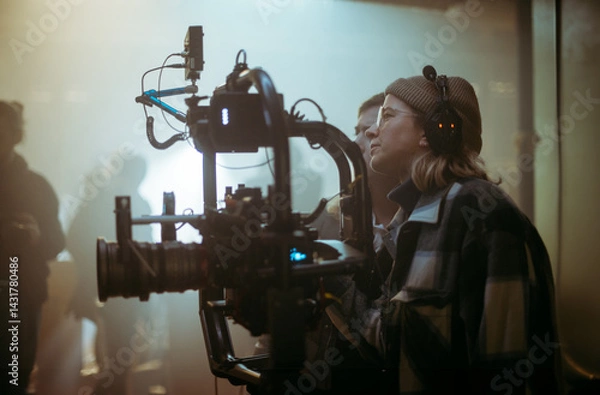 Fototapeta A female director at work on the set. The director works with a band or with a speaker during the filming of a movie, commercial, or television series. The crew, equipment, and crew. 