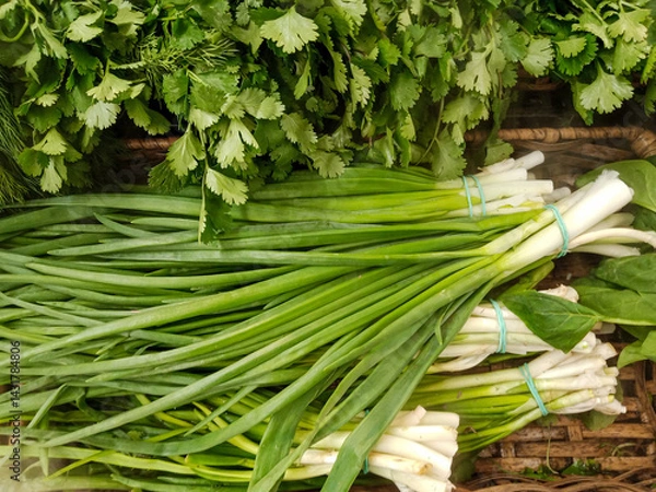 Obraz Freshly picked bunches of green onions and parsley at market in wicker basket, top view