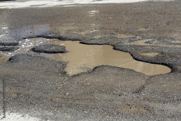 Fototapeta Worn asphalt with a large puddle.