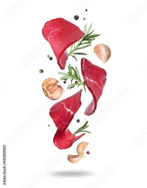 Fototapeta Thinly sliced ​​venison with rosemary and garlic cloves in the air close-up on white background