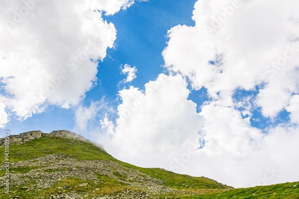 Fototapeta landscape with mountain and blue sky with clouds. alpine adventure. steep hill with stones and grass. beautiful nature of romania in summer