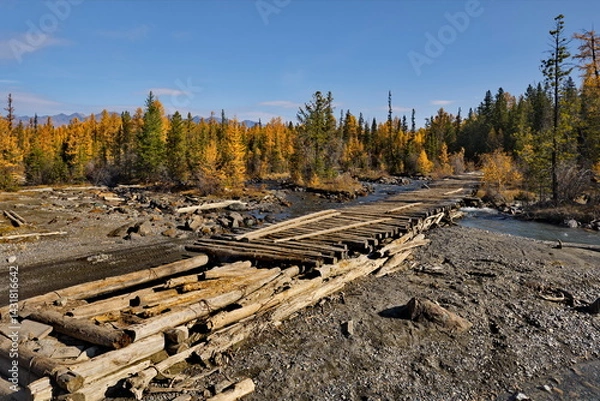 Fototapeta Russia. The Altai Mountains. A dilapidated wooden bridge over the Aktra River, which all-terrain vehicles drive around along the stone riverbed on the way to the ancient glacier of the same name.