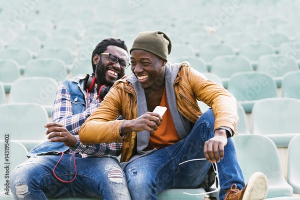 Obraz Two black race friends having fun with mobile.