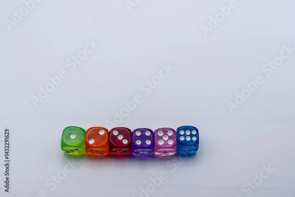 Fototapeta Row of colorful translucent dice in various colors on a light surface