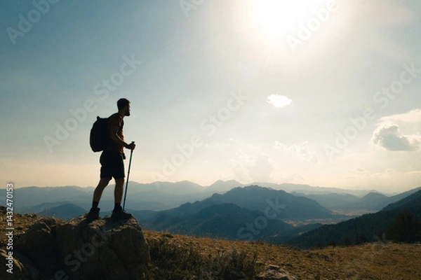 Fototapeta Man climbing to the top of a mountain. Side view of a climber admiring the view of success. Success and adventure.