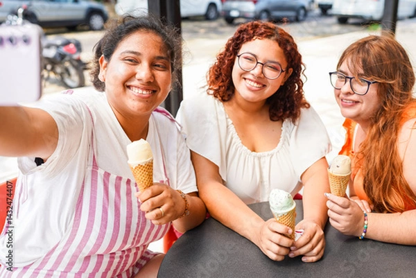Fototapeta Three latin women taking a selfie while enjoying ice cream cones
