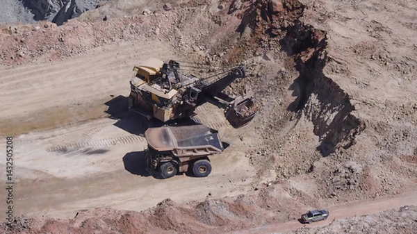 Fototapeta Heavy mining machinery extracting minerals in an open pit mine