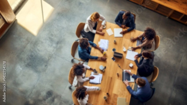 Fototapeta Top view of a blurred team collaborating around a table. office setting filled with motion, brainstorming, and planning energy, symbolizing teamwork, workforce synergy, and modern work culture