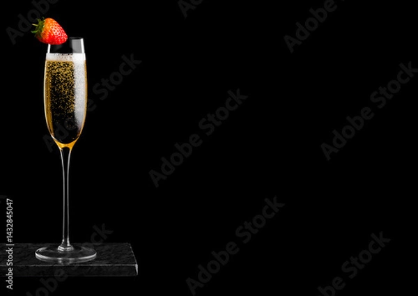 Obraz Elegant glass of yellow champagne with strawberry on top on black marble board on black background. Space for text