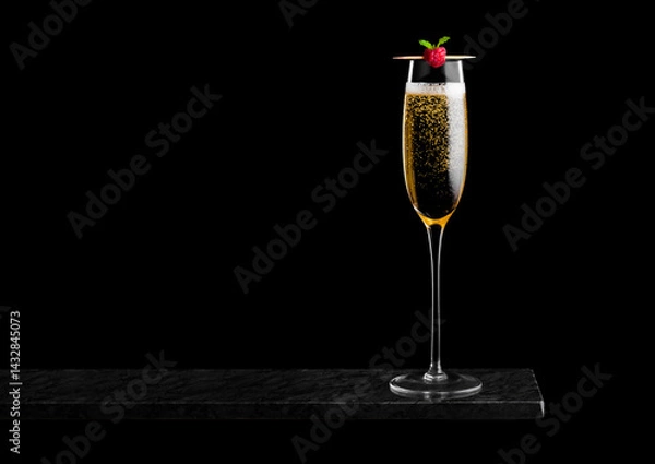 Obraz Elegant glass of yellow champagne with rasspbery on stick on black marble board on black background. Space for text