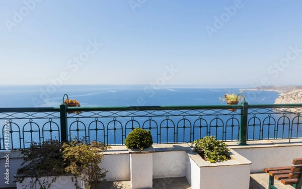 Obraz Beautiful terrace overlooking the expansive sea and coastline. Features sculpted potted plants and an elegant railing, offering a tranquil view for relaxation and travel themes.