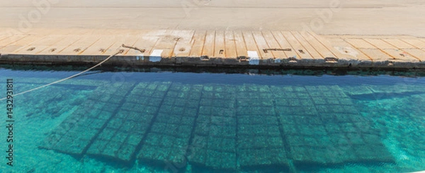 Obraz Crystal Clear Turquoise Water By Weathered Concrete Dock With Reflective Grid Shadows