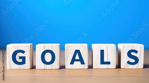 Fototapeta Bright and colorful wooden blocks spelling out goals on a wooden surface with a vibrant blue background symbolizing motivation and achievement