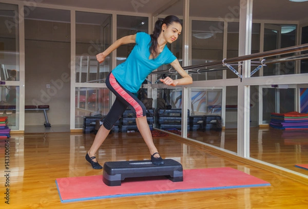Fototapeta girl doing exercises a step platform in the gym, Healthy lifestyle