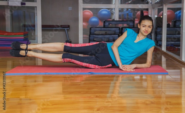 Fototapeta girl doing exercises on Mat in gym