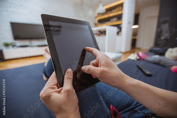 Obraz Close up and part of human hand using digital tablet on sofa