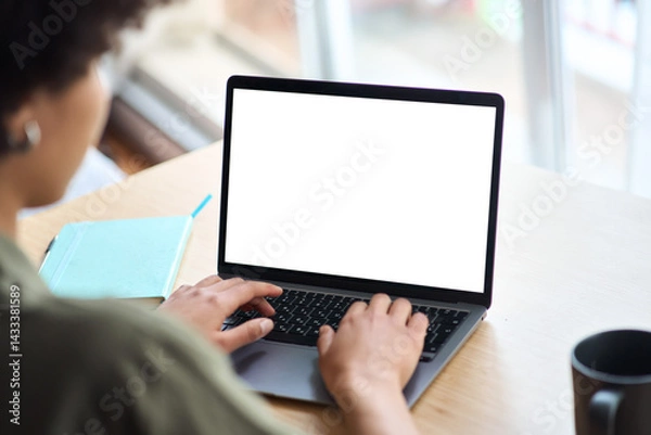 Fototapeta Over shoulder view of African American woman student elearning looking at white mock up blank screen using laptop computer learning online, hybrid working. Website mockup display template for ads.