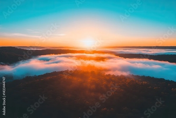 Obraz Sunrise over a valley shrouded in colorful morning mist  Aerial view of a landscape with vibrant colors  Sunrise paints the fog with golden hues, revealing forest below