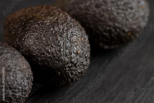 Fototapeta whole avocado fruits of small size on a black slate