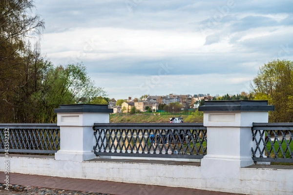 Fototapeta Antique bridge with fence on the background of old town landscape.