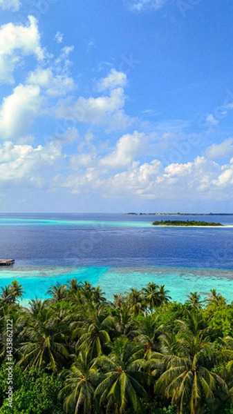 Fototapeta Scenic panoramic view of tropical islands surrounded by deep blue ocean with palm trees in the foreground, maldives summer travel, island getaway, nature beauty
