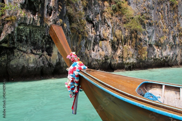 Obraz A close-up view of a traditional longtail boat floating near rugged rocks in Thailand.