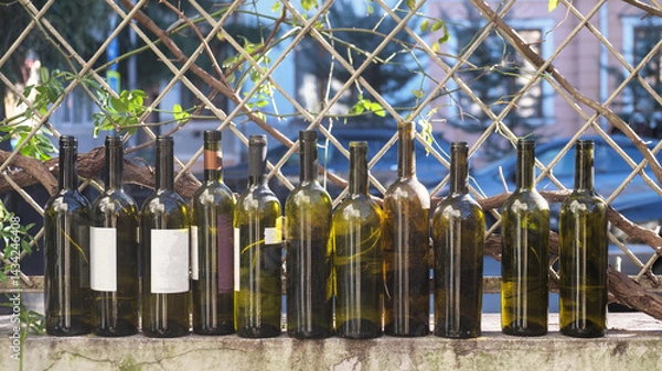 Fototapeta Wine bottles in a row on the fence
